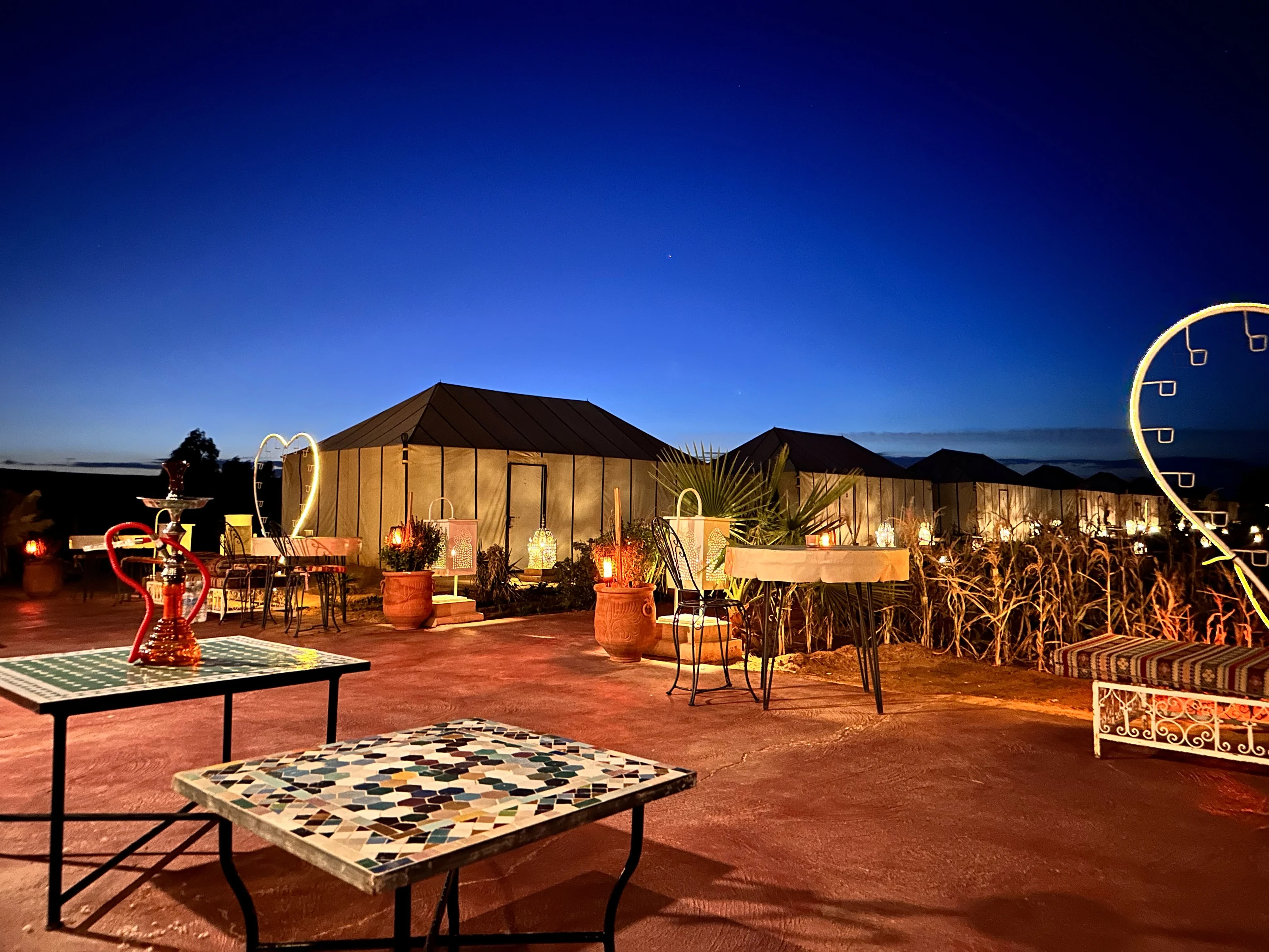 Jaimas y asientos al aire libre iluminados de noche en Golden Camp