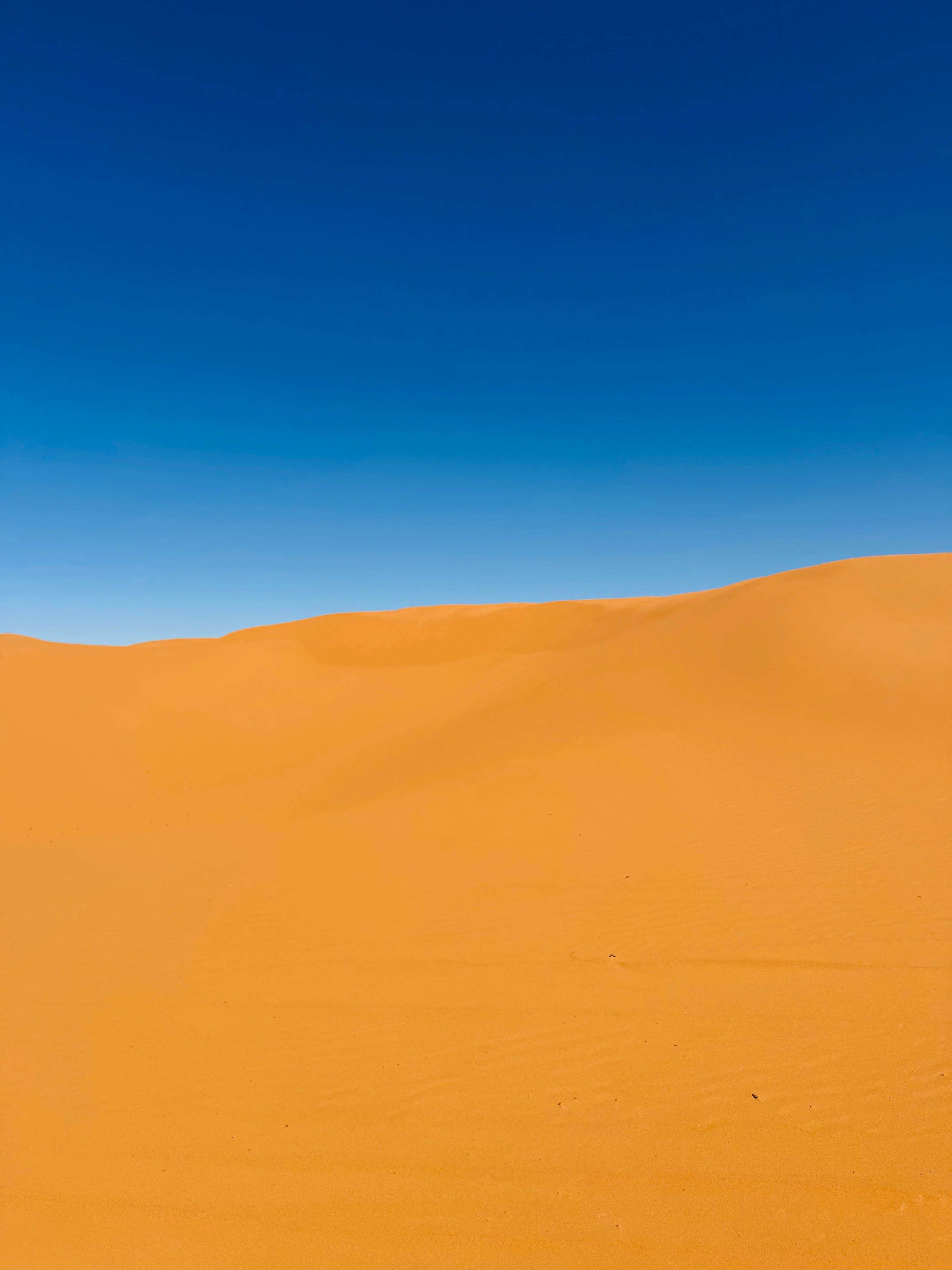Dunas de arena iluminadas por el sol bajo un cielo despejado cerca de Merzouga